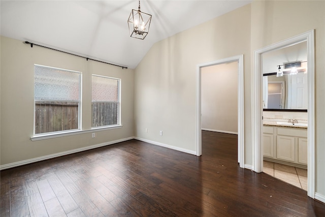 unfurnished room featuring sink, dark hardwood / wood-style flooring, lofted ceiling, and a notable chandelier