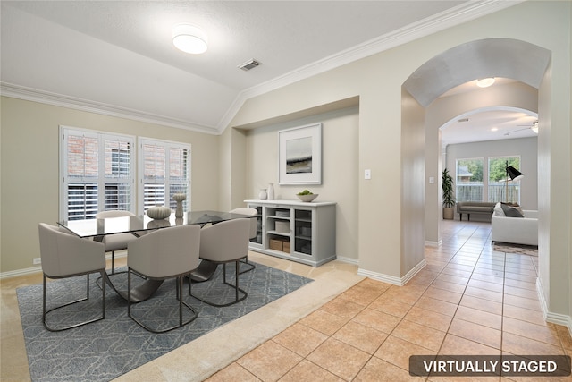 dining space featuring ceiling fan, light tile patterned floors, ornamental molding, and vaulted ceiling