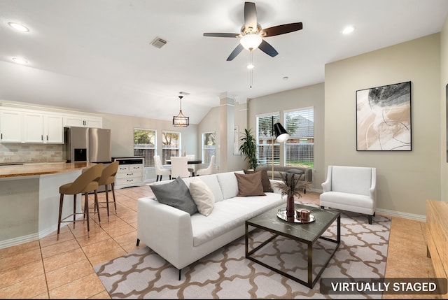 tiled living room featuring ceiling fan with notable chandelier and lofted ceiling