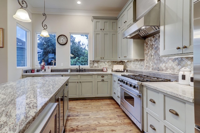 kitchen with light stone counters, ornamental molding, high end stainless steel range oven, wall chimney range hood, and decorative light fixtures