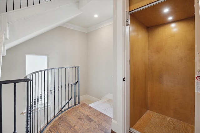 interior space with elevator, crown molding, and light wood-type flooring