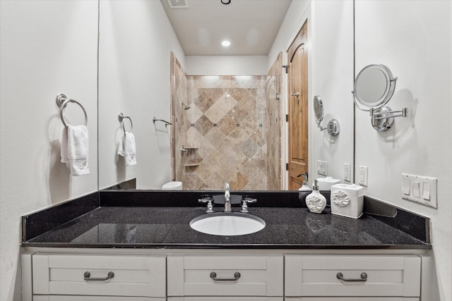 bathroom featuring tiled shower and vanity