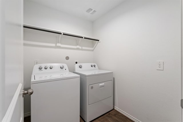 clothes washing area with dark wood-type flooring and washer and clothes dryer