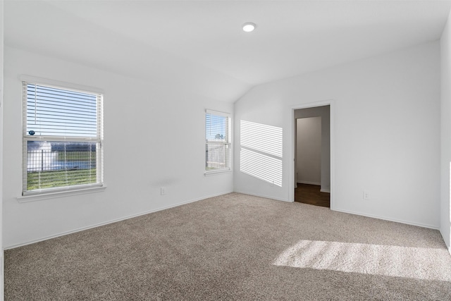 carpeted spare room featuring vaulted ceiling and a healthy amount of sunlight