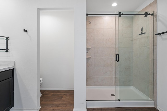 bathroom featuring vanity, wood-type flooring, a shower with door, and toilet