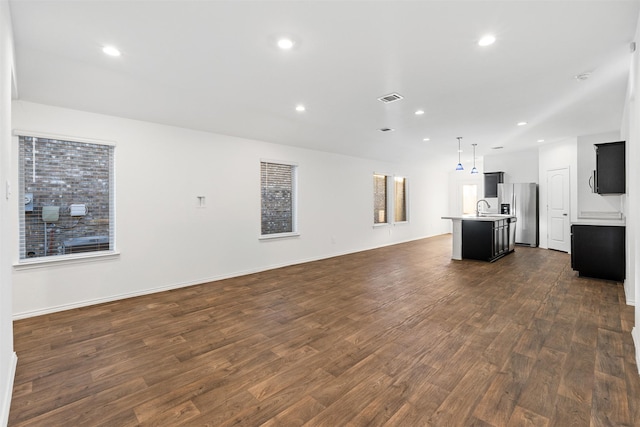 unfurnished living room featuring dark wood-type flooring and sink