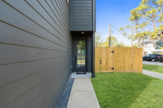 property entrance with fence and a lawn