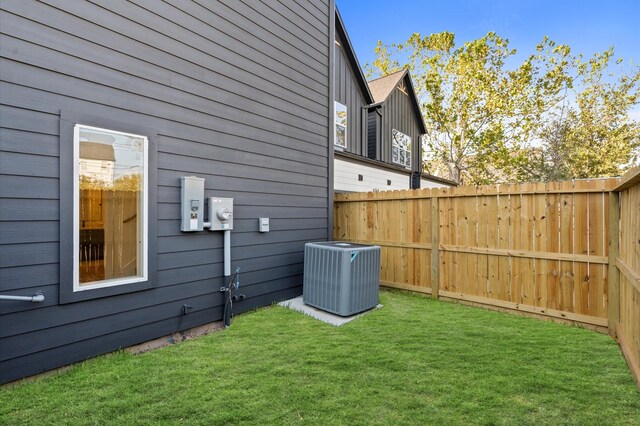 view of side of home with a lawn, fence, and central AC unit