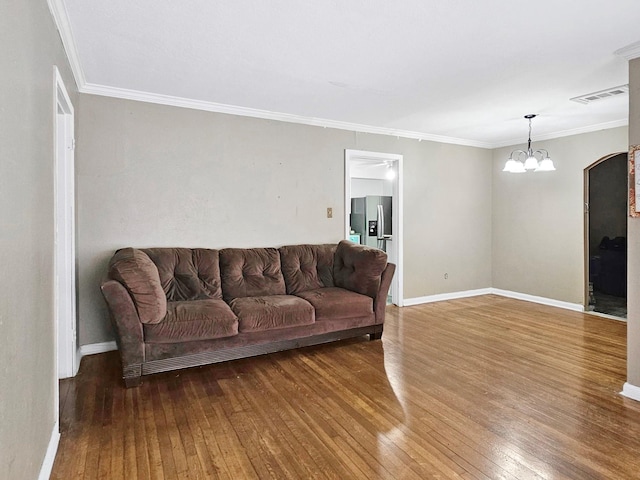 living room featuring hardwood / wood-style flooring, ornamental molding, and an inviting chandelier