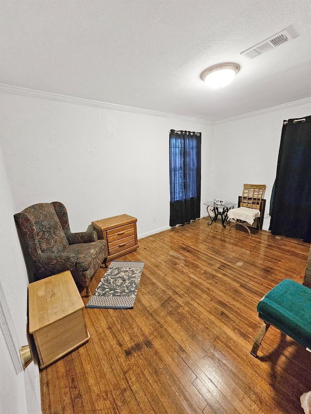 living area featuring hardwood / wood-style floors, a textured ceiling, and ornamental molding