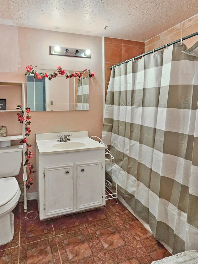 bathroom with a textured ceiling, vanity, and toilet