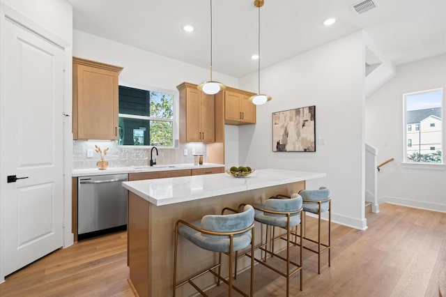 kitchen with pendant lighting, dishwasher, a center island, sink, and light hardwood / wood-style floors