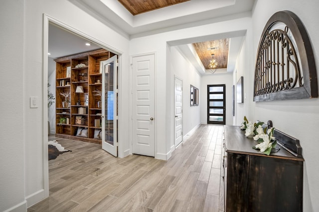 entryway featuring light wood-type flooring, french doors, wood ceiling, a notable chandelier, and a raised ceiling