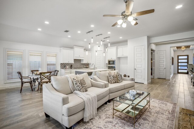 living room featuring light hardwood / wood-style floors, sink, and ceiling fan