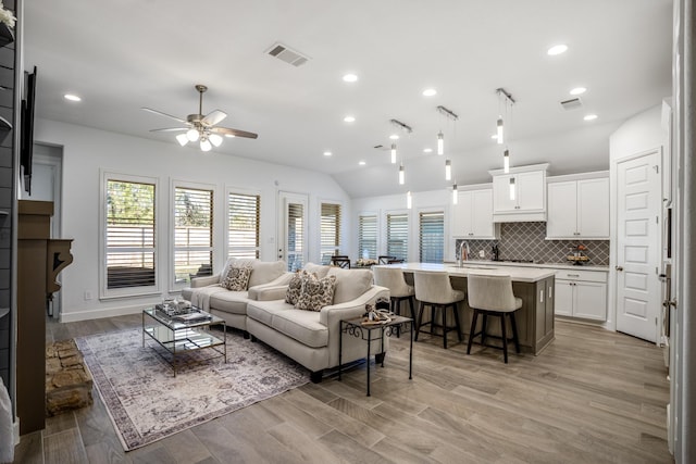 living room featuring ceiling fan, light hardwood / wood-style floors, vaulted ceiling, and a healthy amount of sunlight