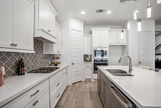 kitchen featuring decorative light fixtures, sink, stainless steel appliances, and white cabinets