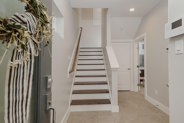 staircase featuring tile patterned floors and vaulted ceiling