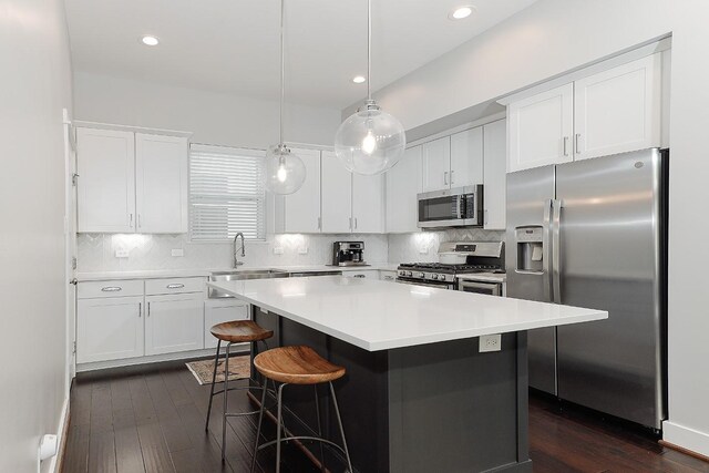 kitchen featuring pendant lighting, white cabinets, sink, appliances with stainless steel finishes, and a kitchen island