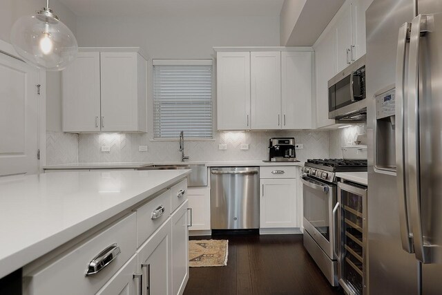 kitchen with white cabinets, dark hardwood / wood-style floors, pendant lighting, and stainless steel appliances