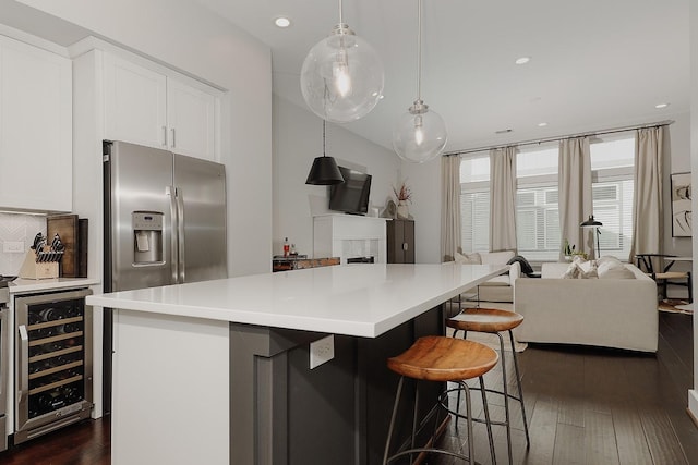 kitchen with white cabinetry, a kitchen island, beverage cooler, and decorative light fixtures