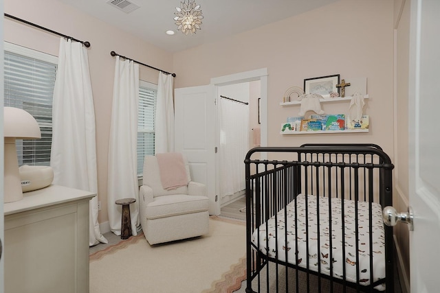 bedroom featuring a nursery area and a notable chandelier