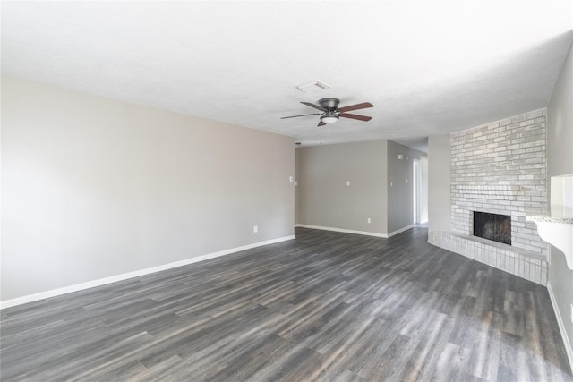 unfurnished living room with ceiling fan, dark hardwood / wood-style floors, a brick fireplace, and a textured ceiling