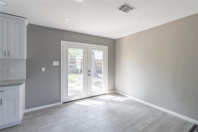 entryway with french doors and a textured ceiling