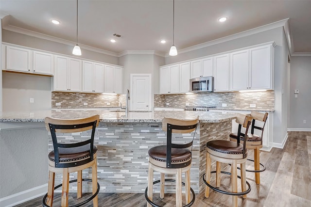 kitchen with decorative light fixtures, white cabinetry, and light stone counters