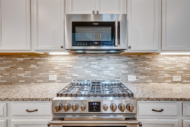 kitchen with backsplash, light stone counters, and stainless steel appliances