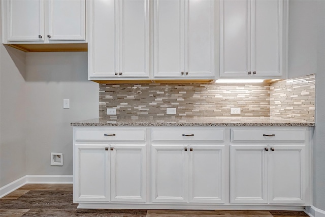 kitchen with backsplash, white cabinetry, and light stone counters