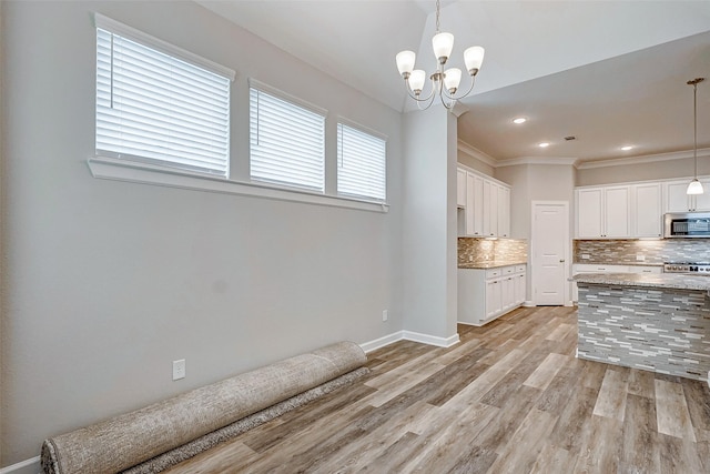 kitchen featuring tasteful backsplash, stainless steel appliances, decorative light fixtures, an inviting chandelier, and white cabinetry