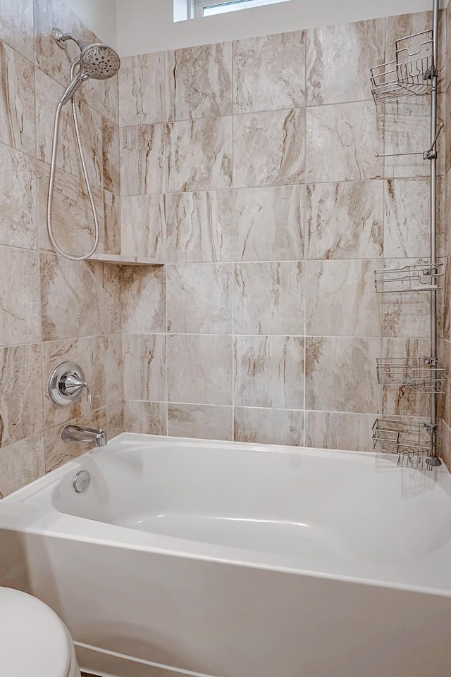 bathroom featuring toilet and tiled shower / bath