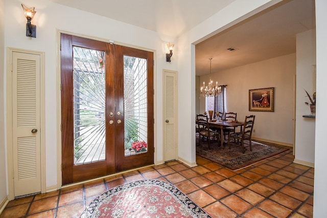 entrance foyer with tile patterned flooring, an inviting chandelier, and french doors