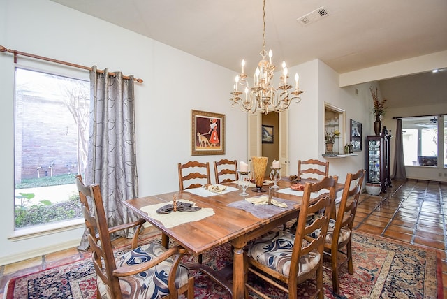 dining room featuring plenty of natural light, dark tile patterned floors, and an inviting chandelier