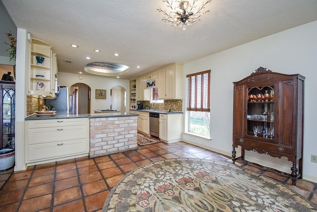 kitchen with a textured ceiling, decorative backsplash, dishwasher, and dark tile patterned flooring