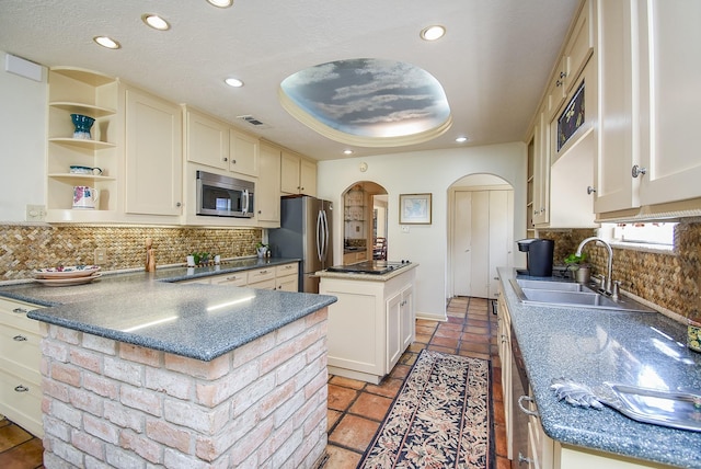 kitchen featuring sink, a center island, a raised ceiling, decorative backsplash, and appliances with stainless steel finishes