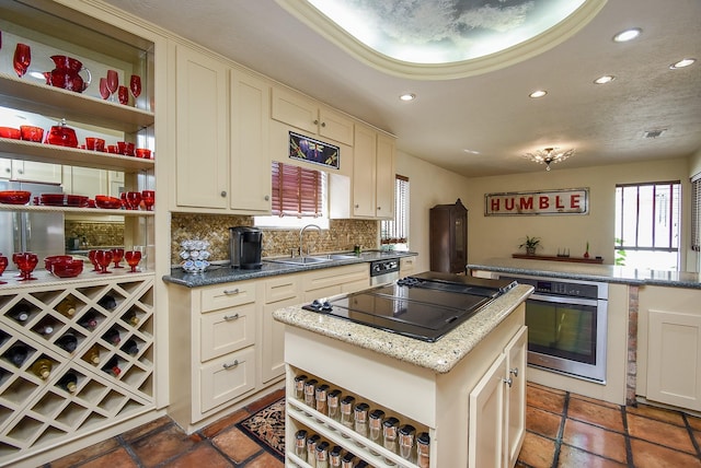 kitchen featuring backsplash, sink, light stone countertops, a kitchen island, and stainless steel appliances