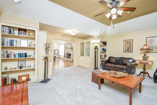 carpeted living room with vaulted ceiling, a brick fireplace, and ceiling fan