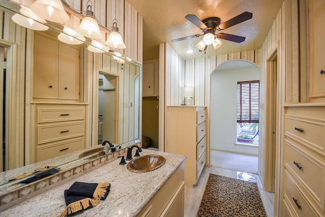 bathroom featuring vanity, ceiling fan, wood-type flooring, and a textured ceiling