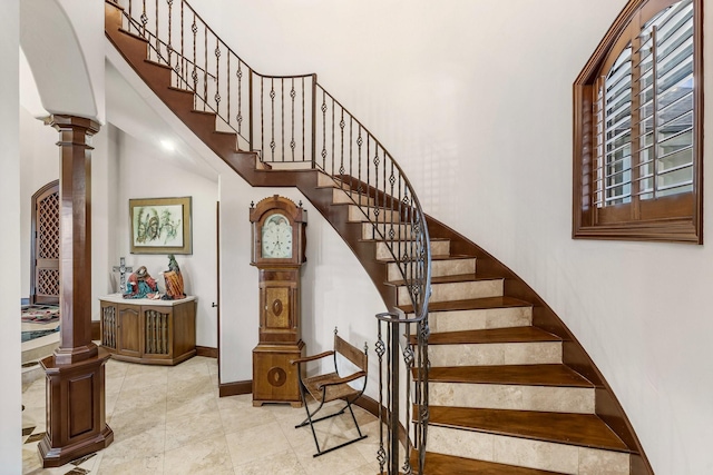 staircase featuring a high ceiling and decorative columns