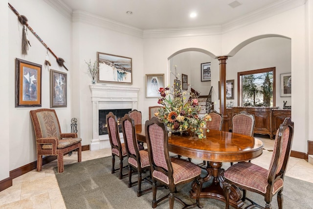 tiled dining space featuring crown molding and decorative columns