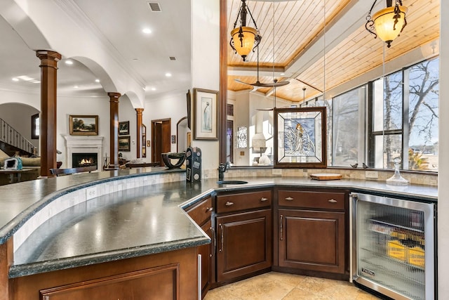 kitchen with wooden ceiling, sink, ornate columns, decorative light fixtures, and beverage cooler