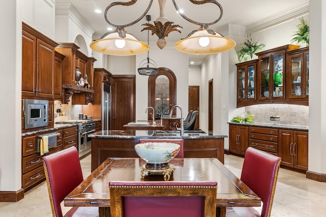 kitchen featuring built in appliances, decorative backsplash, sink, and an island with sink