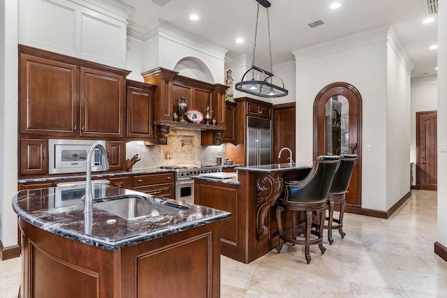 kitchen featuring sink, hanging light fixtures, built in appliances, decorative backsplash, and a large island