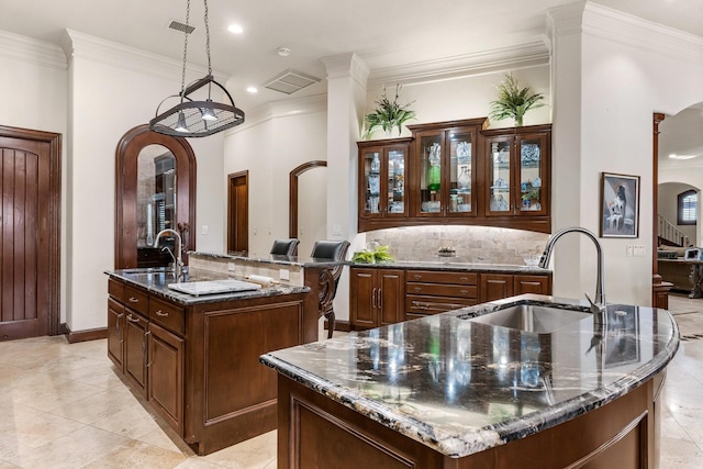 kitchen with dark stone counters, a spacious island, and sink