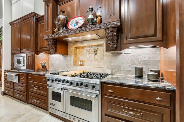 kitchen featuring stainless steel appliances, dark stone counters, decorative backsplash, light tile patterned floors, and custom exhaust hood