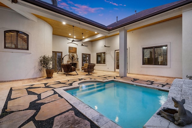 pool at dusk with ceiling fan and a patio area