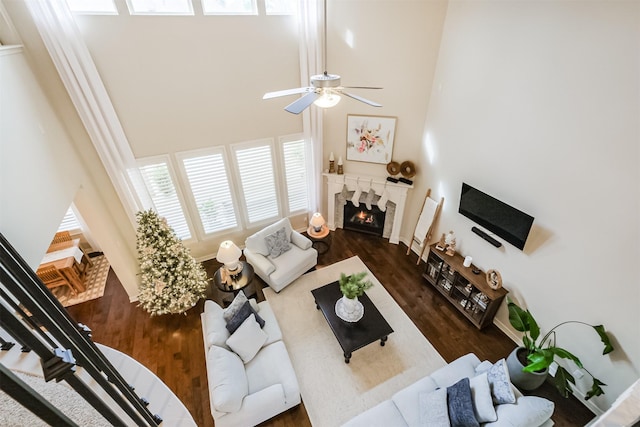 living room with dark hardwood / wood-style flooring, a towering ceiling, and ceiling fan