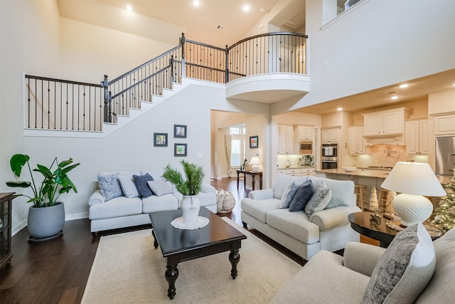 living room with dark hardwood / wood-style floors and a towering ceiling