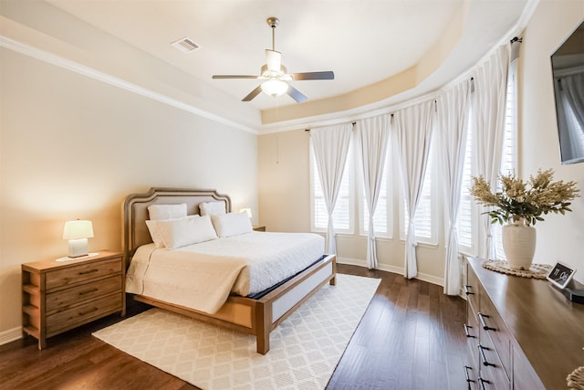 bedroom with a raised ceiling, ceiling fan, and dark hardwood / wood-style floors